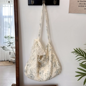 Detail of off-white canvas shoulder bag with blue butterfly prints and lace trim