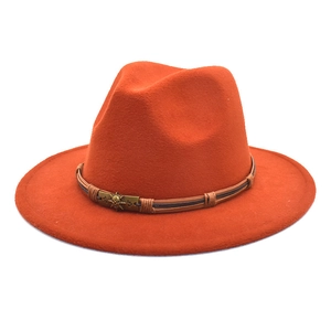 Close-up of orange wool fedora hat featuring a brown braided band and punk skull emblem