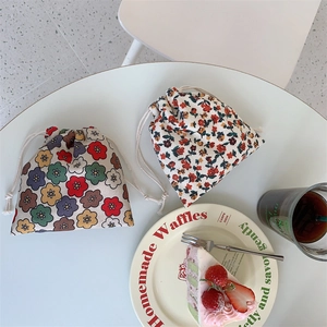 Corduroy drawstring storage pouches with floral patterns on a cozy tea time table