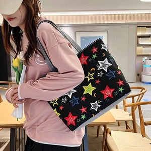 Detail of canvas tote bag featuring colorful star print and sturdy grey shoulder straps