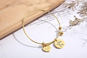 Close-up of gold heart and mi mama pendants on adjustable stainless steel bracelet