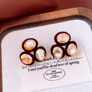 Detail view of retro oval champagne crystals on dark red velvet earring studs