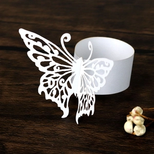 Detailed laser-cut white butterfly paper napkin ring on a dark rustic wooden background