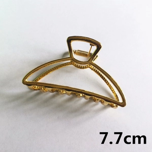 Detail view of a 7.7cm golden metal hair claw clip with a semi-circular hollow design