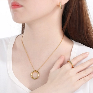 Elegant gold stainless steel jewelry set with circular crystal pendant and ring on model