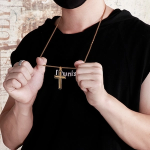 Close-up of a gold layered cross pendant necklace with black inlay on a male model