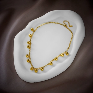Elegant gold titanium steel necklace with spherical beads on O-chain over silk background