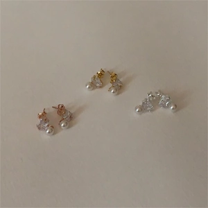 Detail of 925 silver stud earrings set featuring square zircons and round white pearls