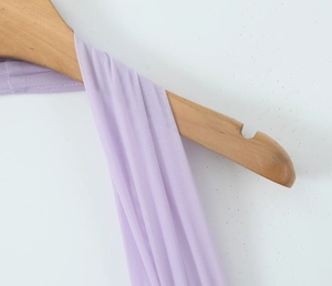 Détail du tissu en maille violette et des fines bretelles sur un cintre en bois