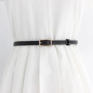 Minimalist black slim leather belt for women with golden rectangular buckle on white dress