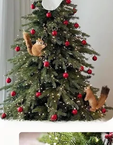 Close-up of lifelike brown squirrel and red baubles on a lit Christmas tree