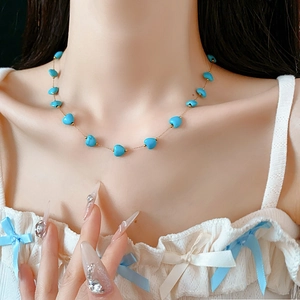Detail of bohemian heart-shaped turquoise pendant necklace on a gold chain
