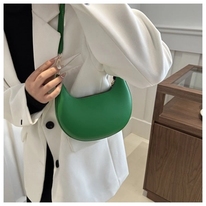Detail of vibrant green hobo shoulder bag with crescent design on white blazer outfit