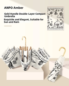 Detail of elegant cream folding umbrella with floral print and golden curved handle
