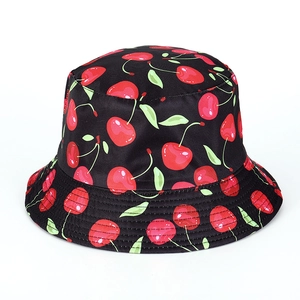 Close-up of a black bucket hat featuring a vibrant all-over red cherry and green leaf print