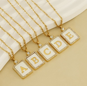Detail of square gold pendants with crystal-studded letters and white shell inlay