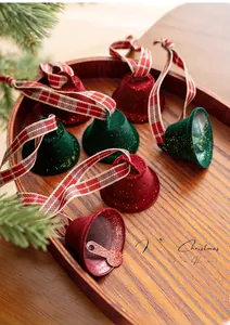 Detail of red and green flocked Christmas bells with festive ribbons on a wooden tray