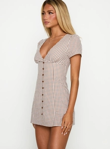 Detail shot of the V-neckline and button-down front on the brown plaid mini dress
