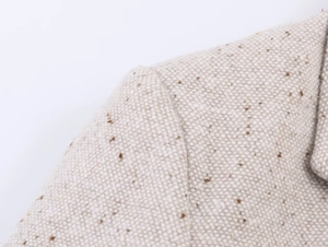 Gros plan détaillé sur la texture en tweed beige et les coutures d'épaule du blazer