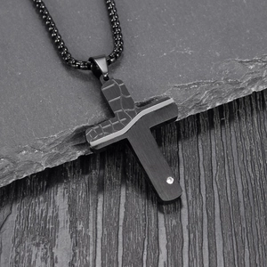 Detail of black cracked cross pendant with crocodile texture and diamond accent