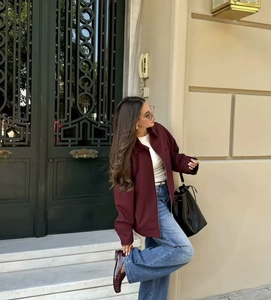Street style shot of a burgundy jacket paired with blue straight jeans and loafers