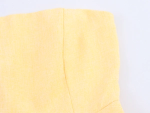 Vista macro del tessuto in tweed giallo chiaro che mostra la trama incrociata e la cucitura