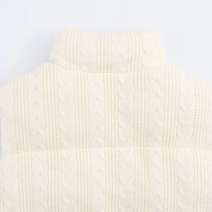 Close-up of cream knit vest featuring cable stitch texture and elegant high-collar neck