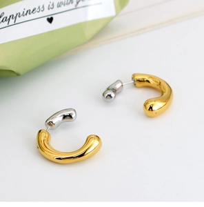 Macro detail of U-shaped mixed metal earrings with polished gold and silver finish