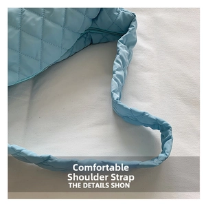 Detail of comfortable wide padded shoulder strap on blue quilted puffer bag