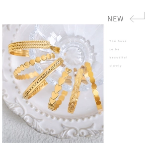 Detailed view of a six-piece set of gold-plated hip-hop style open bangles in varied textures
