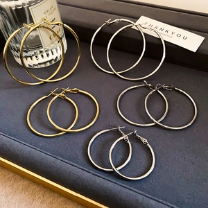 Flat lay of gold and silver hoop earrings in small, medium, and large sizes on a tray