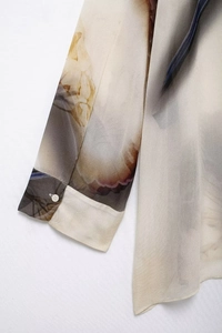 Dettaglio della manica in chiffon con stampa astratta e polsino con bottone bianco