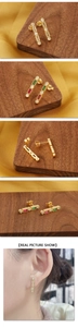 Detailed view of rectangular gold earrings with champagne zircons on yellow silk background
