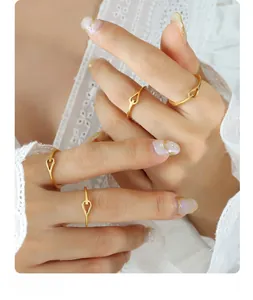 Close-up of minimalist 18K gold-plated stacking rings with hollow knot designs on fingers