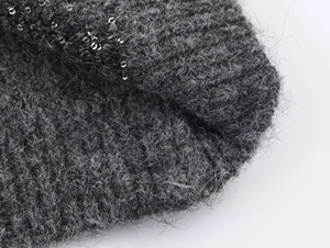 Primer plano de tejido de punto gris con textura suave y detalles de lentejuelas plata