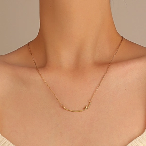 Dettaglio della collana con pendente a sorriso in acciaio inossidabile dorato e fiocco sulla clavicola
