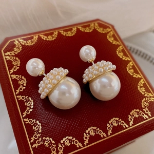Gros plan de boucles d'oreilles doubles perles avec accents dorés sur un coffret rouge