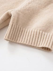 Close-up of oatmeal knit sweater fabric showing soft texture and ribbed cuff detail