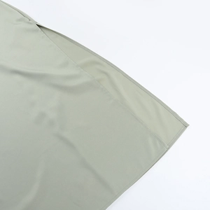 Détail des coutures fines et de la fente sur une robe de soirée en satin vert sauge