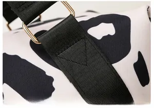 Close-up of cow print oxford bag with reinforced stitching and gold metal buckles