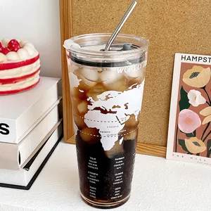 Large 1L glass coffee mug with world map print and stainless steel straw on a cozy desk