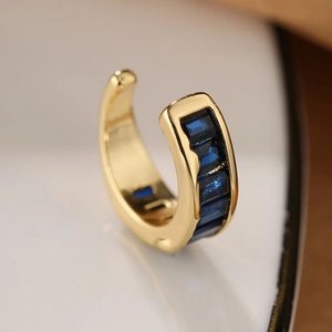 Macro shot of 18K gold plated ear cuff featuring emerald-cut blue cubic zirconia stones