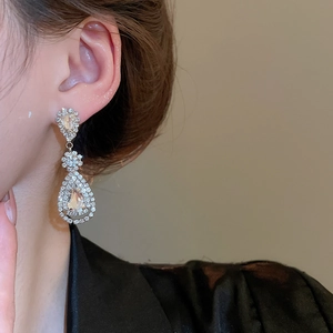 Close-up of silver water drop tassel earrings with sparkling crystals on female model