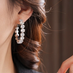 Close-up of elegant silver hoop earrings with shimmering crystal rhinestones on model