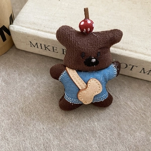 Detailed view of a plush brown bear hair clip wearing a blue tee and guitar bag