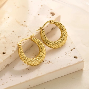 Détail macro de boucles d'oreilles créoles en acier titane plaqué or 18k à billes texturées