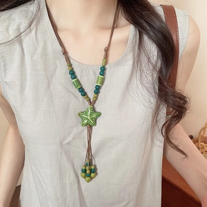Detail of green ceramic starfish pendant necklace on model with braided rope tassels