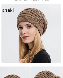 Détail du bonnet en maille kaki avec bouton en bois et pompon en fausse fourrure