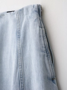Detail van een lichtblauwe denim jeans met een metalen rits aan de zijkant en nauwkeurige naden