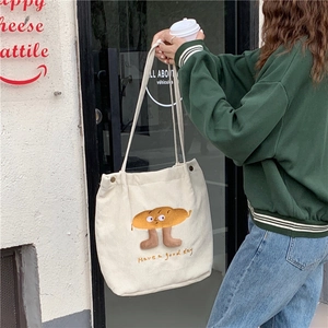 Détail du sac cabas en velours côtelé blanc cassé avec broderie pain et bandoulière
